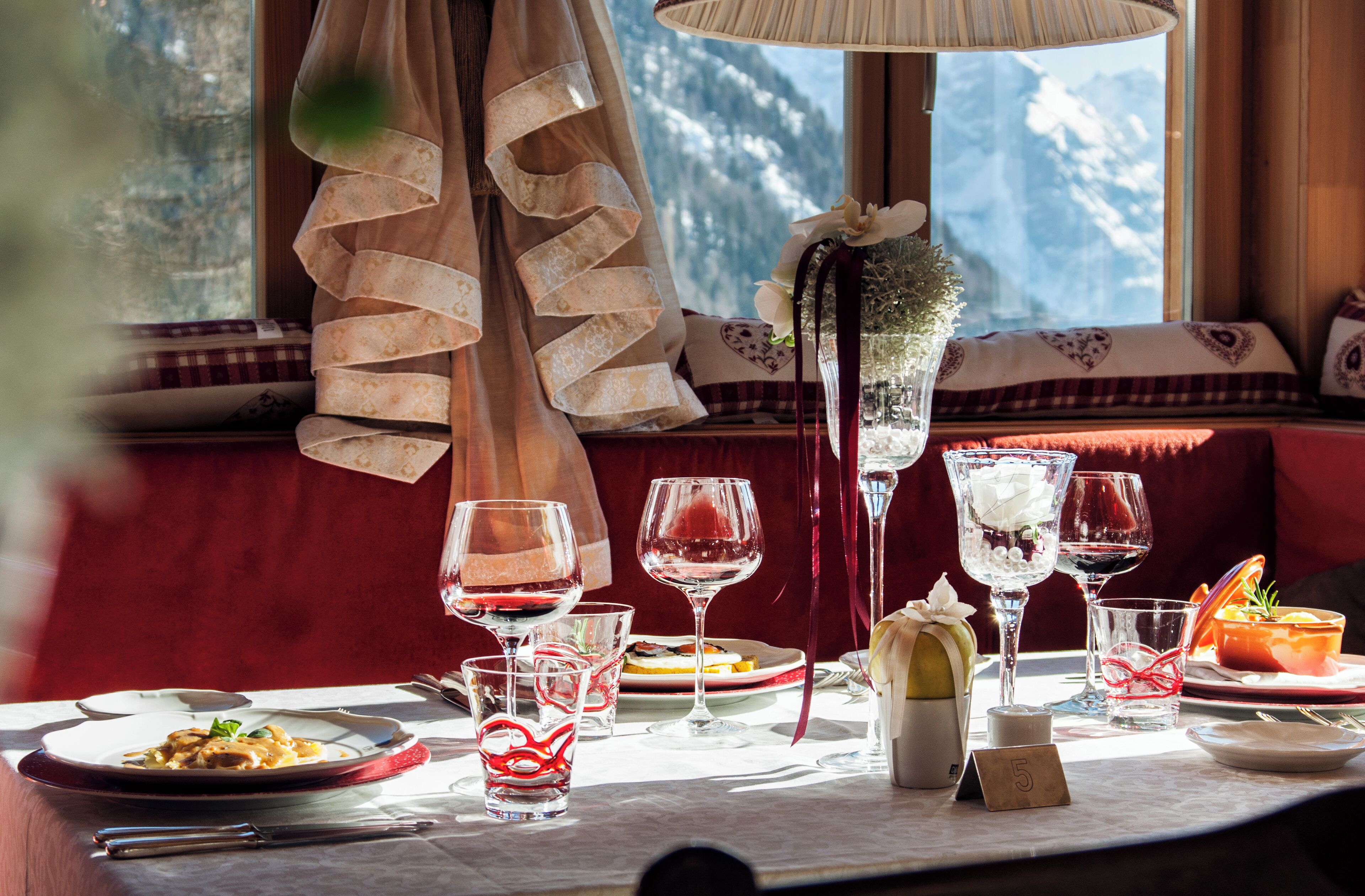 A dining table with multiple wine glasses, plates of food, and a candle.