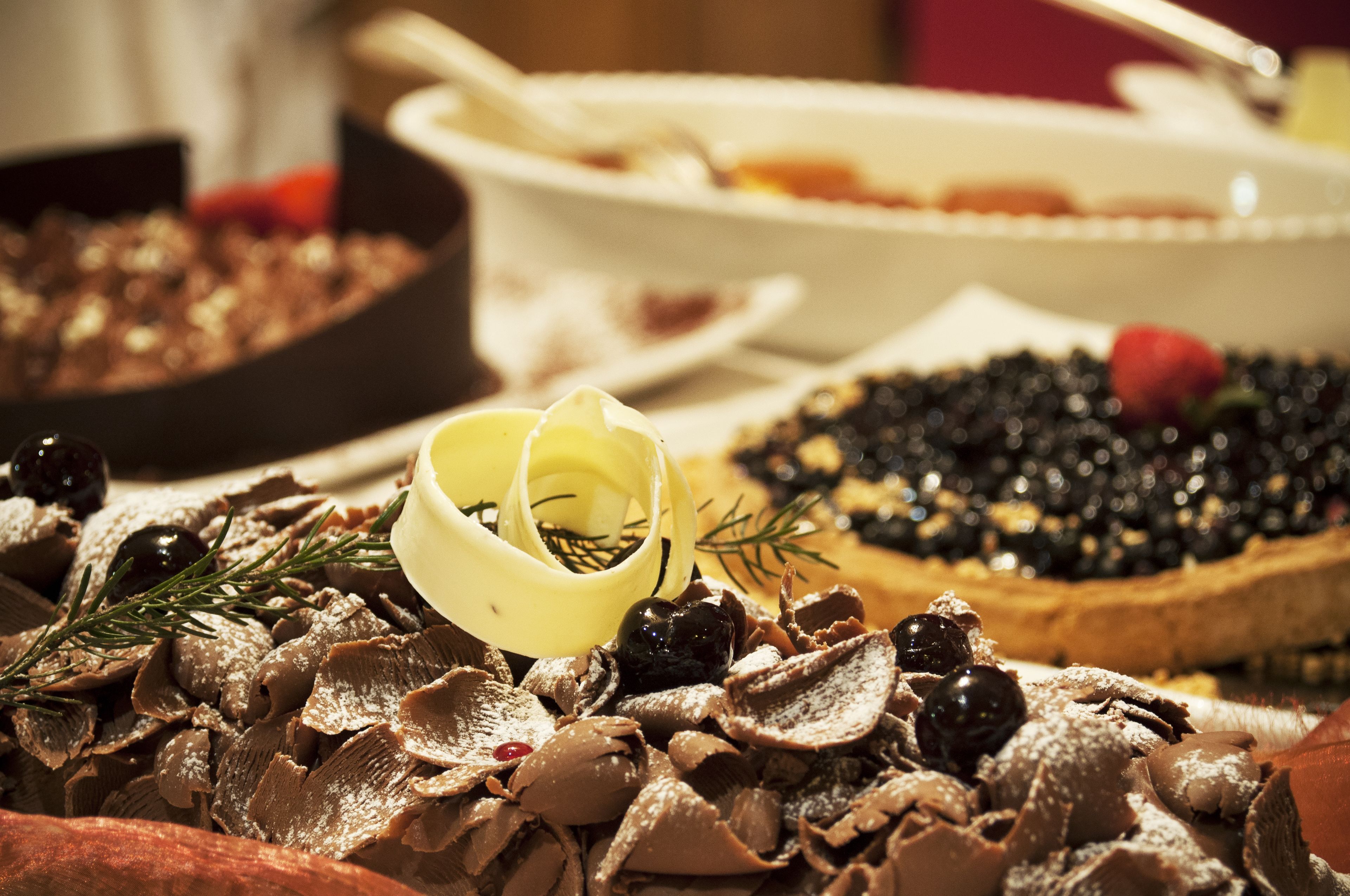 A dessert table with various chocolate treats, including a chocolate tart with berries and a chocolate-covered banana.
