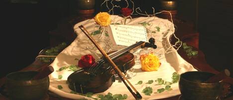 A violin, sheet music, and two roses on a table with a cloth.