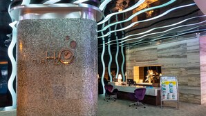 A reception area with a mosaic-patterned pillar, a reception desk, and a signboard. - Hotel H2O (Manila)