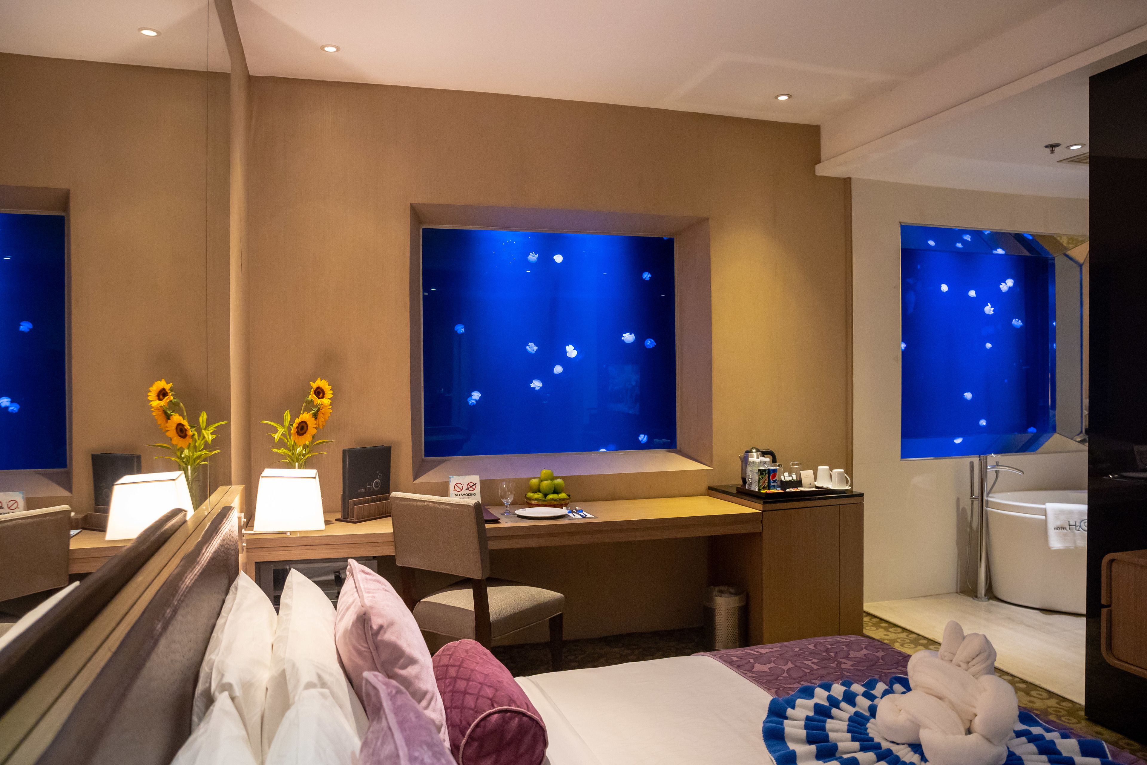 Habitación de hotel con cama, escritorio y un ventanal con vistas a la ciudad.