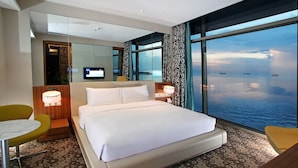 A hotel room with a large bed, a small table, a chair, and a TV. - Hotel H2O (Manila)