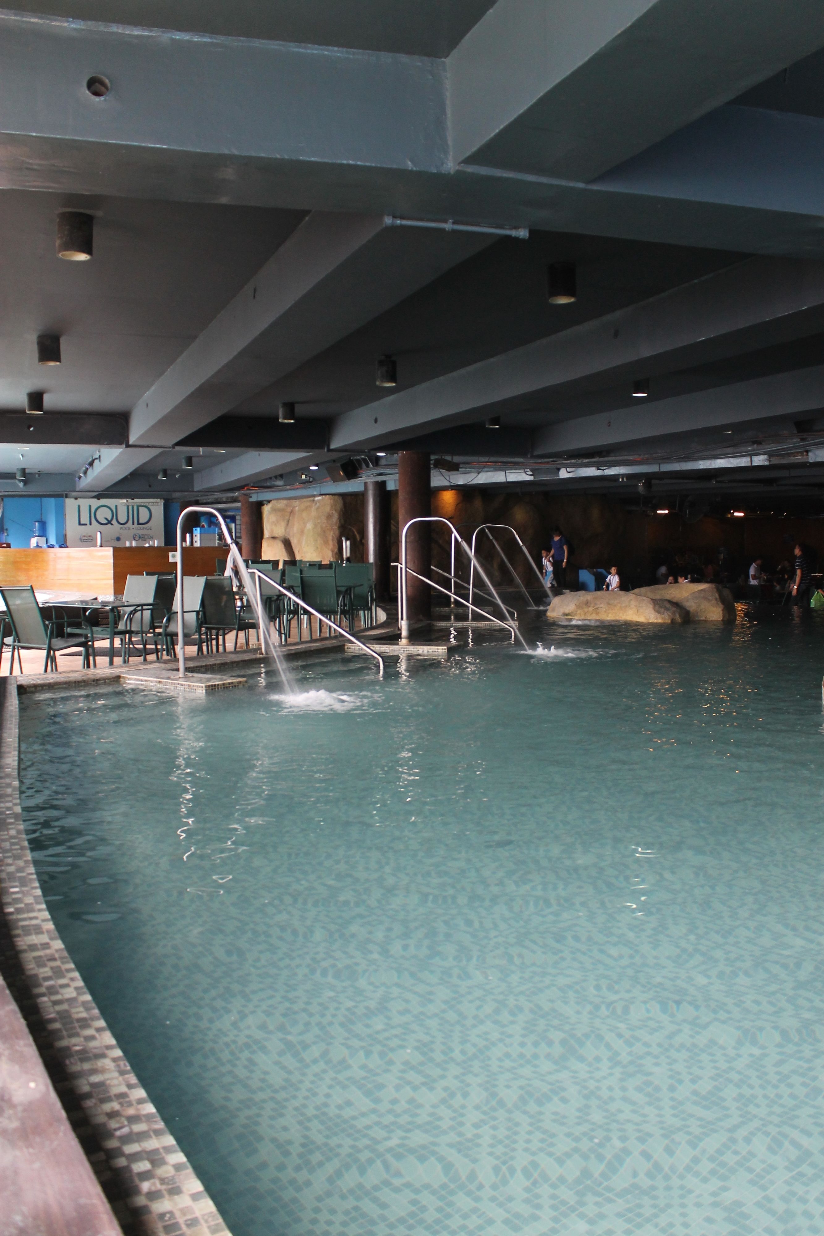 An indoor swimming pool with a diving board and steps leading into the water.
