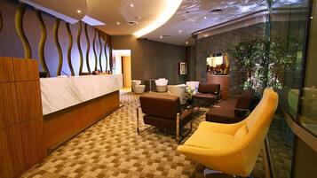 A hotel lobby with a reception desk, seating area, and a large window with a view.