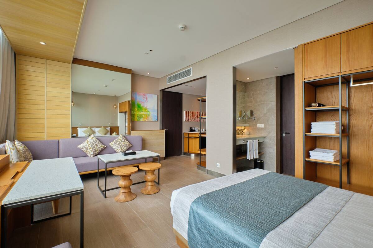 Ett modernt hotellrum med en säng, en soffa, ett skrivbord och ett badrum.