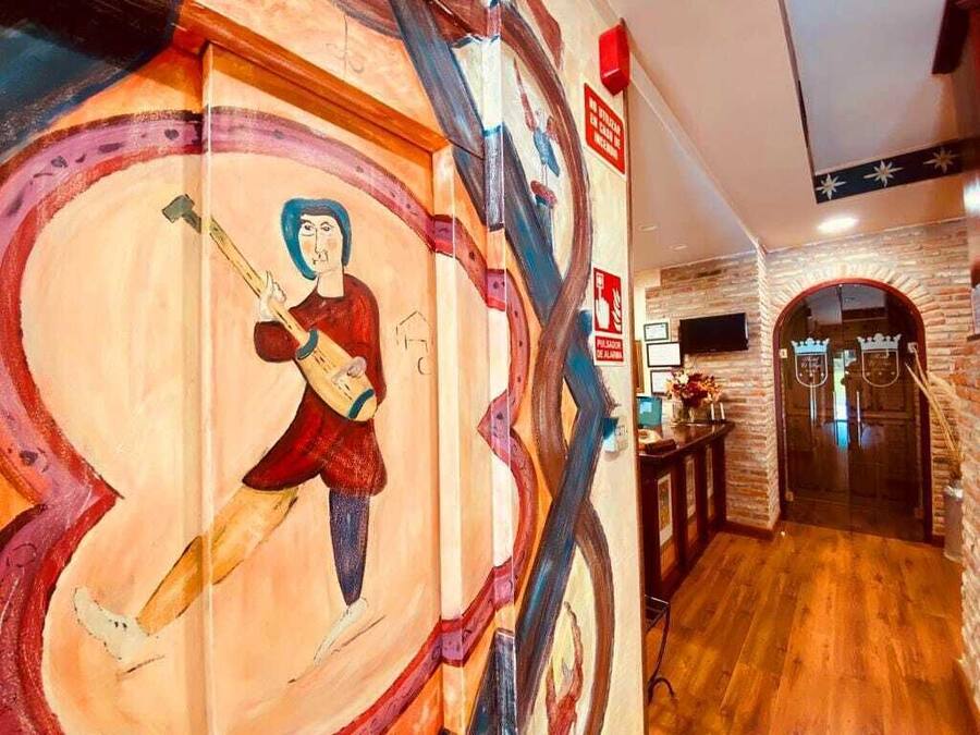 A hallway with a mural of a person playing a guitar, a brick wall, and a wooden floor.