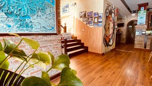 Un hall d’entrée avec un plancher en bois, un escalier et une grande fresque murale.