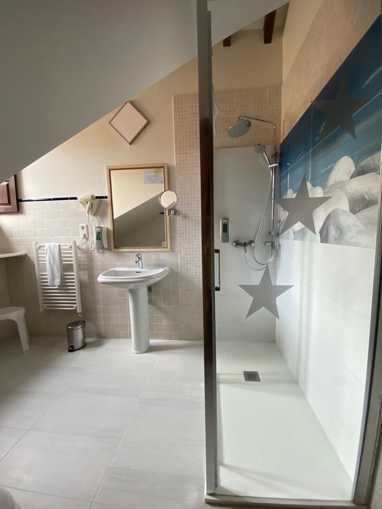 A modern bathroom with a glass shower enclosure, a pedestal sink, a towel rack, and a mirror.