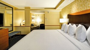 A hotel room with a large bed, a desk, a chair, a TV, and a mirror. - Fairfield Inn & Suites by Marriott Tampa Fairgrounds/Casino (Tampa)