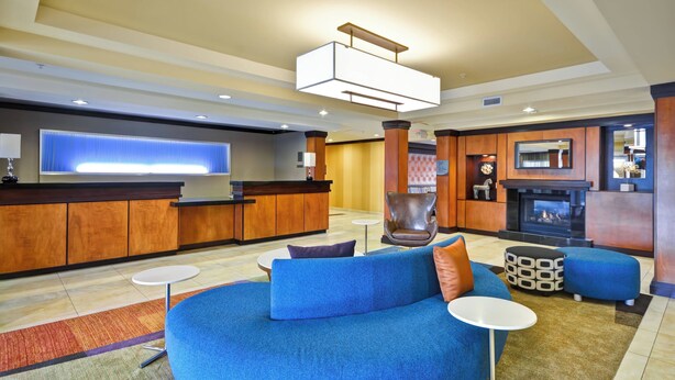 A modern living room with a blue sofa, a fireplace, a TV, and a kitchen area. - Fairfield Inn & Suites by Marriott Tampa Fairgrounds/Casino (Tampa)