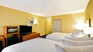 A hotel room with two beds, a television, a microwave, a desk, and a wardrobe.