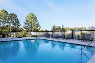 A swimming pool with lounge chairs and a fence.