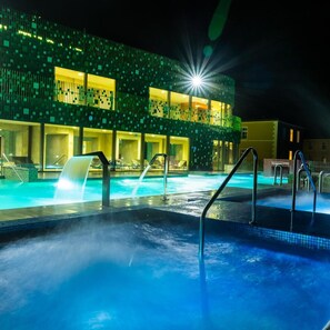 Una piscina techada, una piscina al aire libre, sombrillas