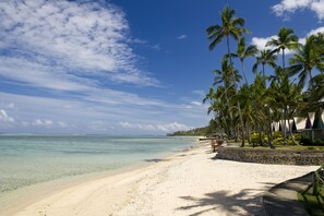 En privat strand, hvidt sand, liggestole, parasoller