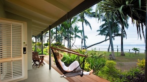 A woman relaxing in a hammock on a wooden deck with a view of palm trees and the ocean. - Fiji Hideaway Resort and Spa (Korolevu)