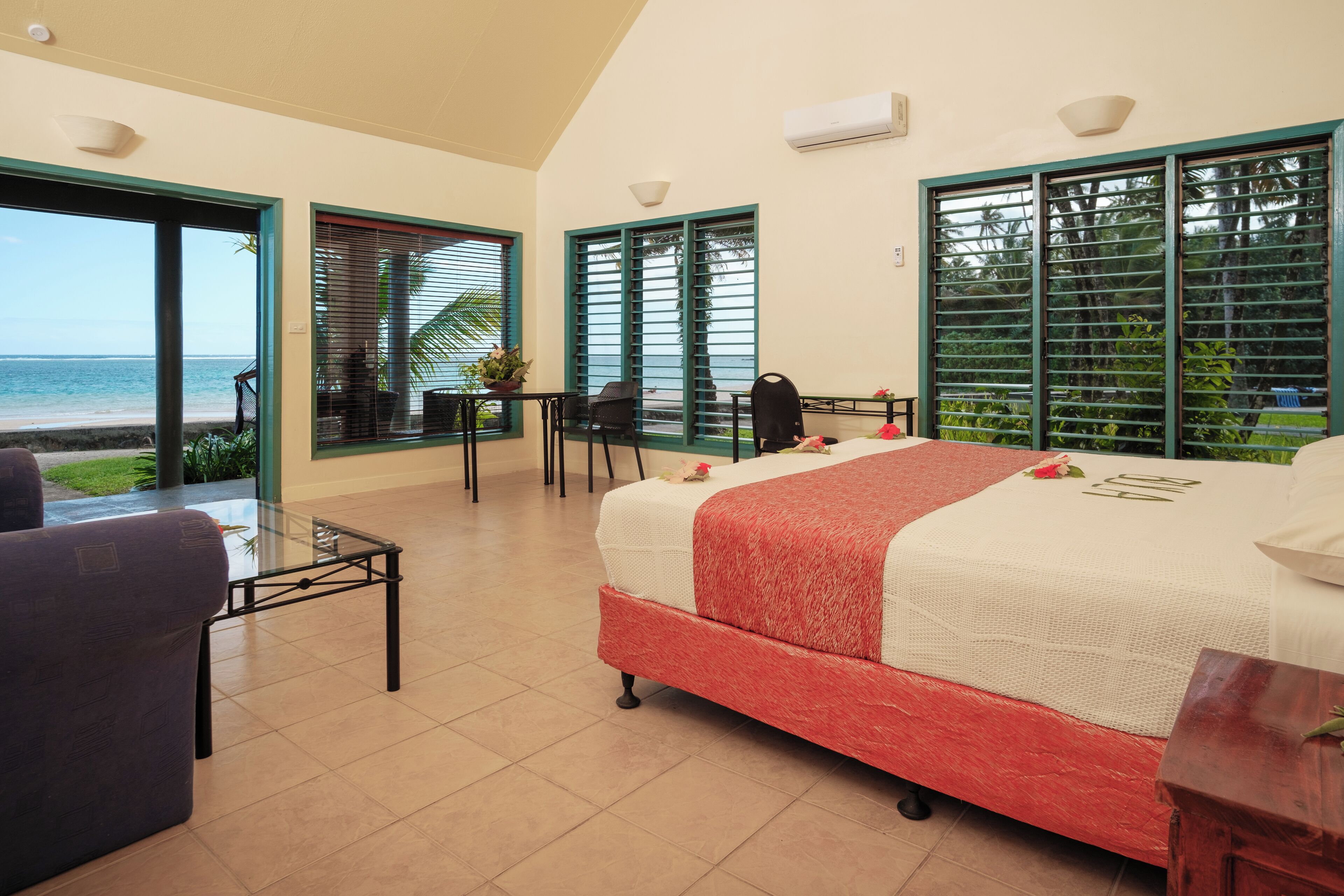 Una camera d'albergo con un letto, un tavolo e vista sulla spiaggia.