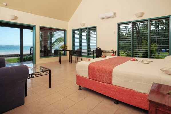 Habitación de hotel con cama, una mesa y vista a la playa.