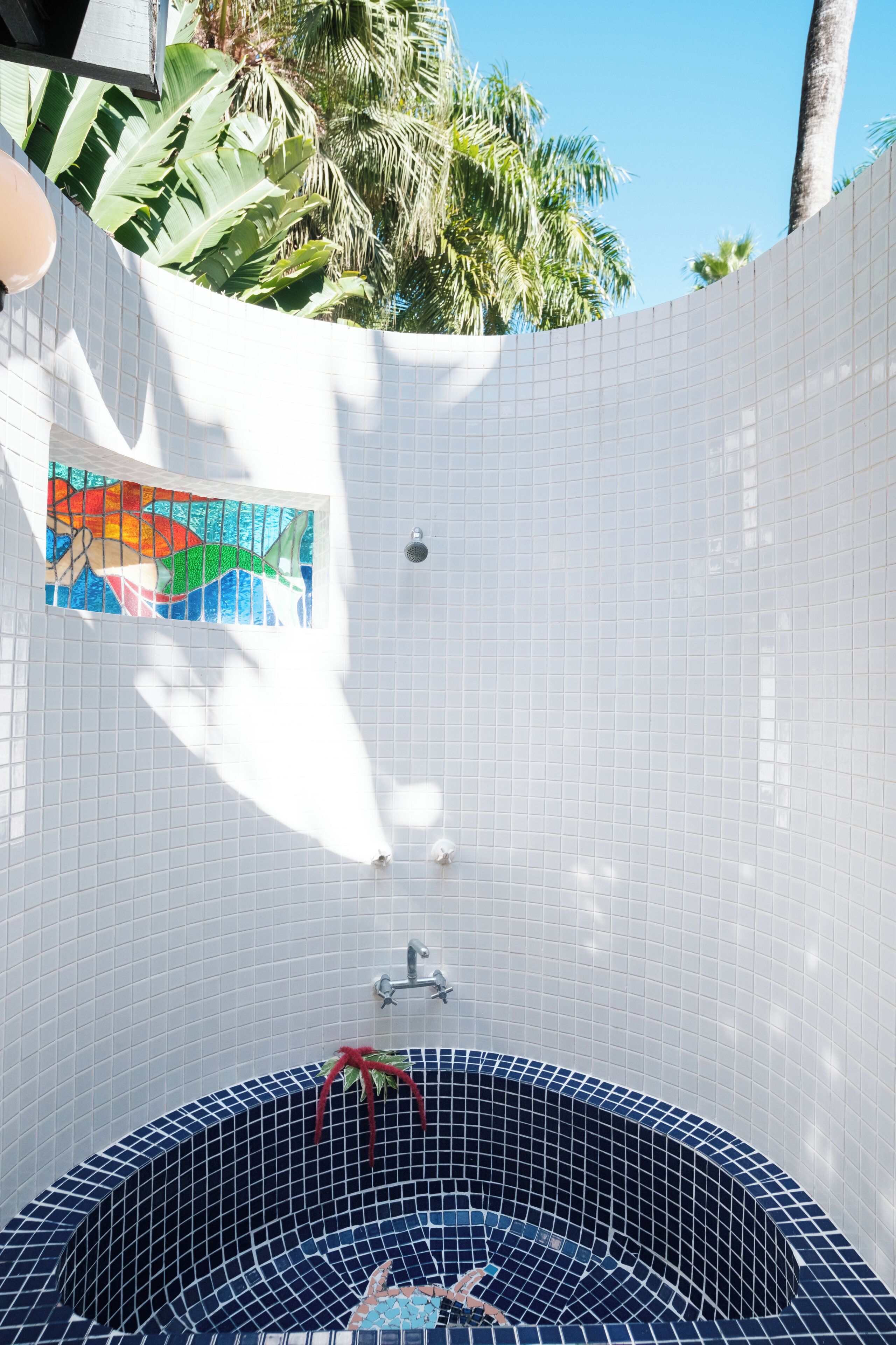 Un baño con pared de azulejos, zona de ducha y bañera con mosaicos azules.