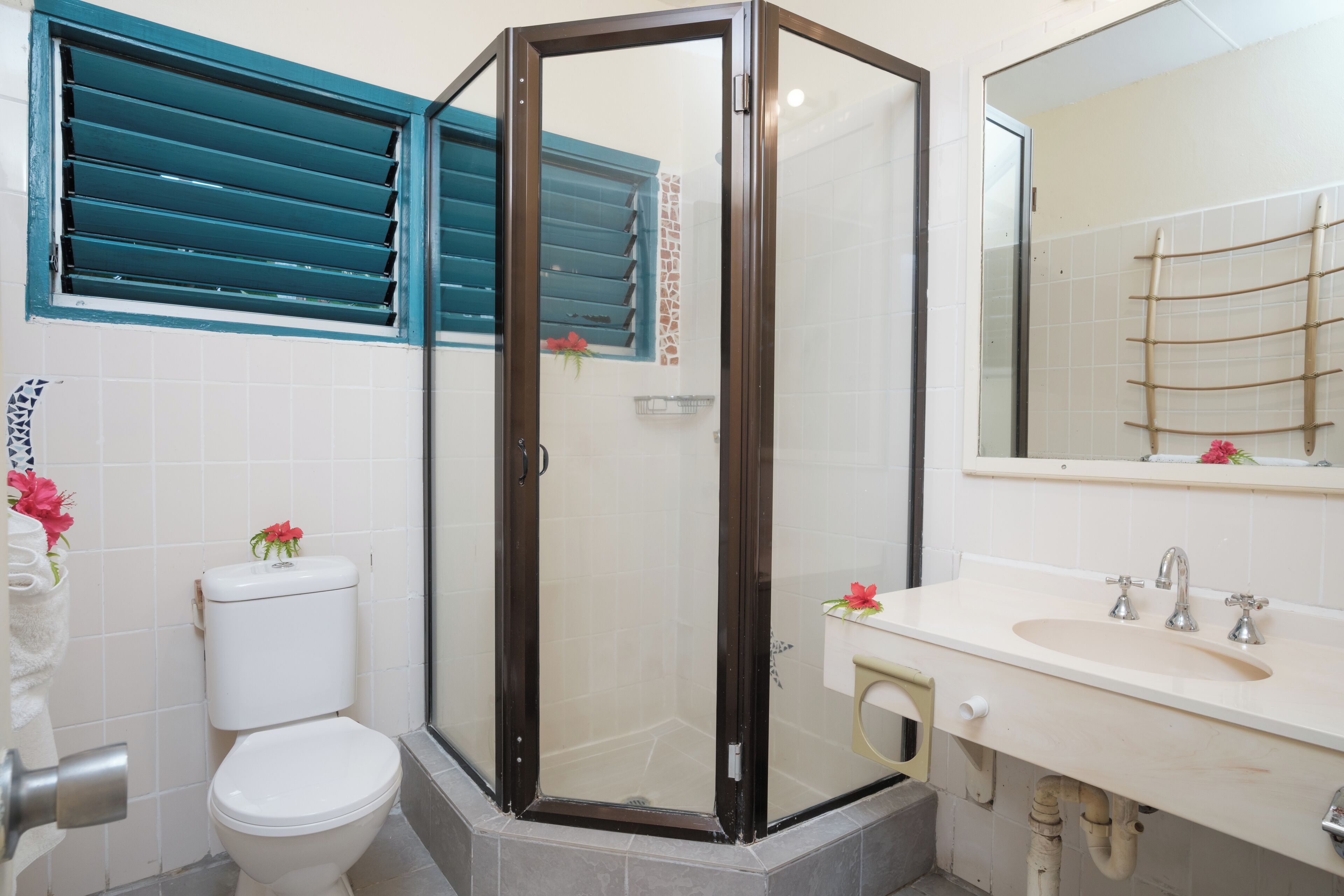 Un baño con inodoro, cabina de ducha y lavamanos con espejo.