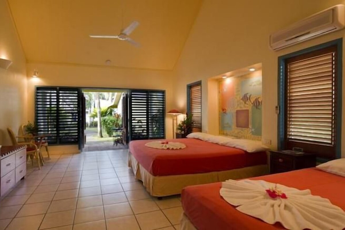 A hotel room with two beds, a desk, a chair, and a view of the outdoors.
