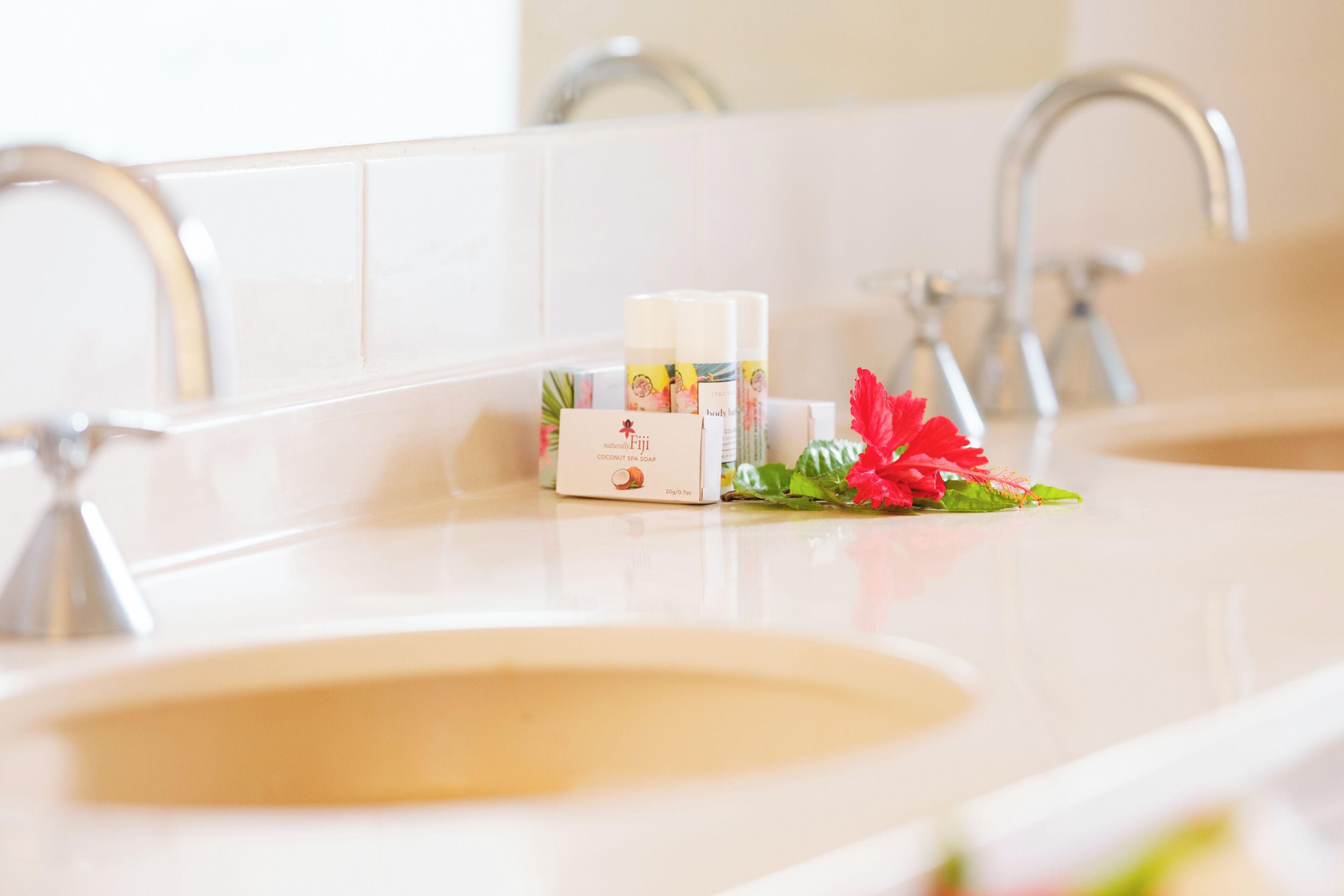 A bathroom with two sinks, a mirror, and a floral arrangement on the counter.