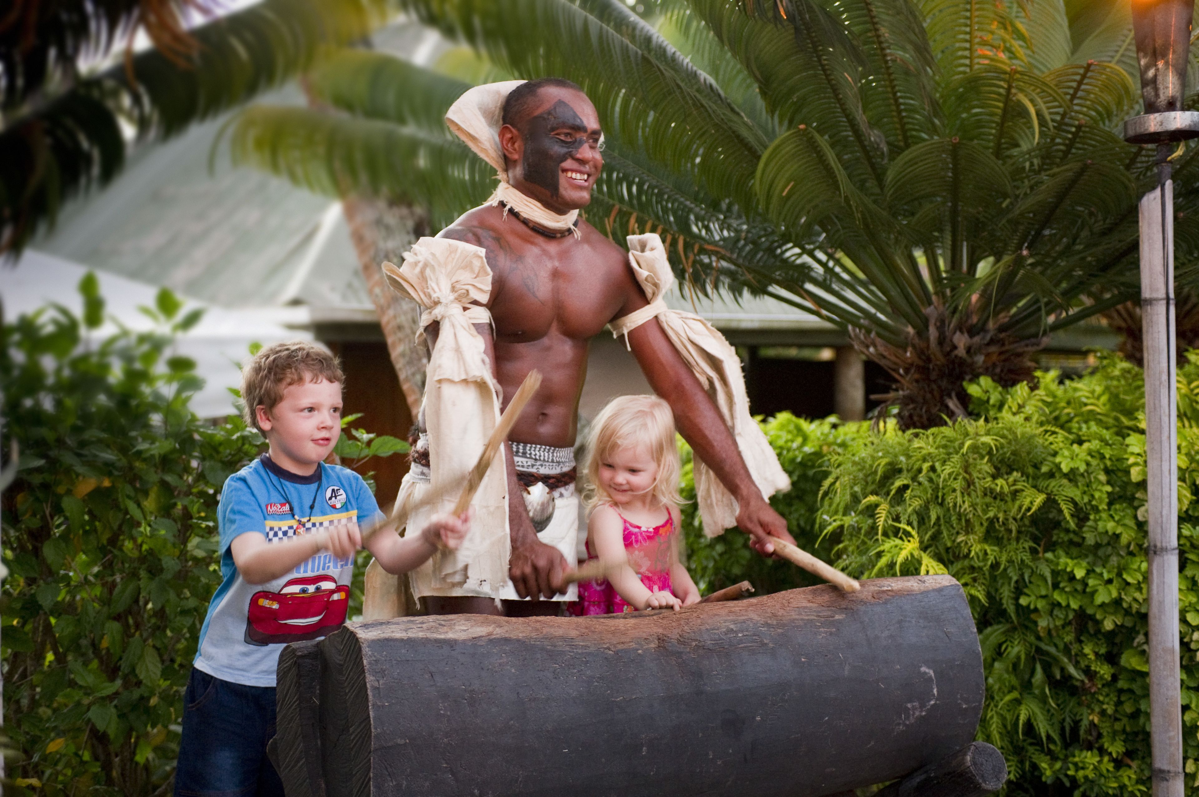 A statue of a man with a child and a young girl in front of a large log.
