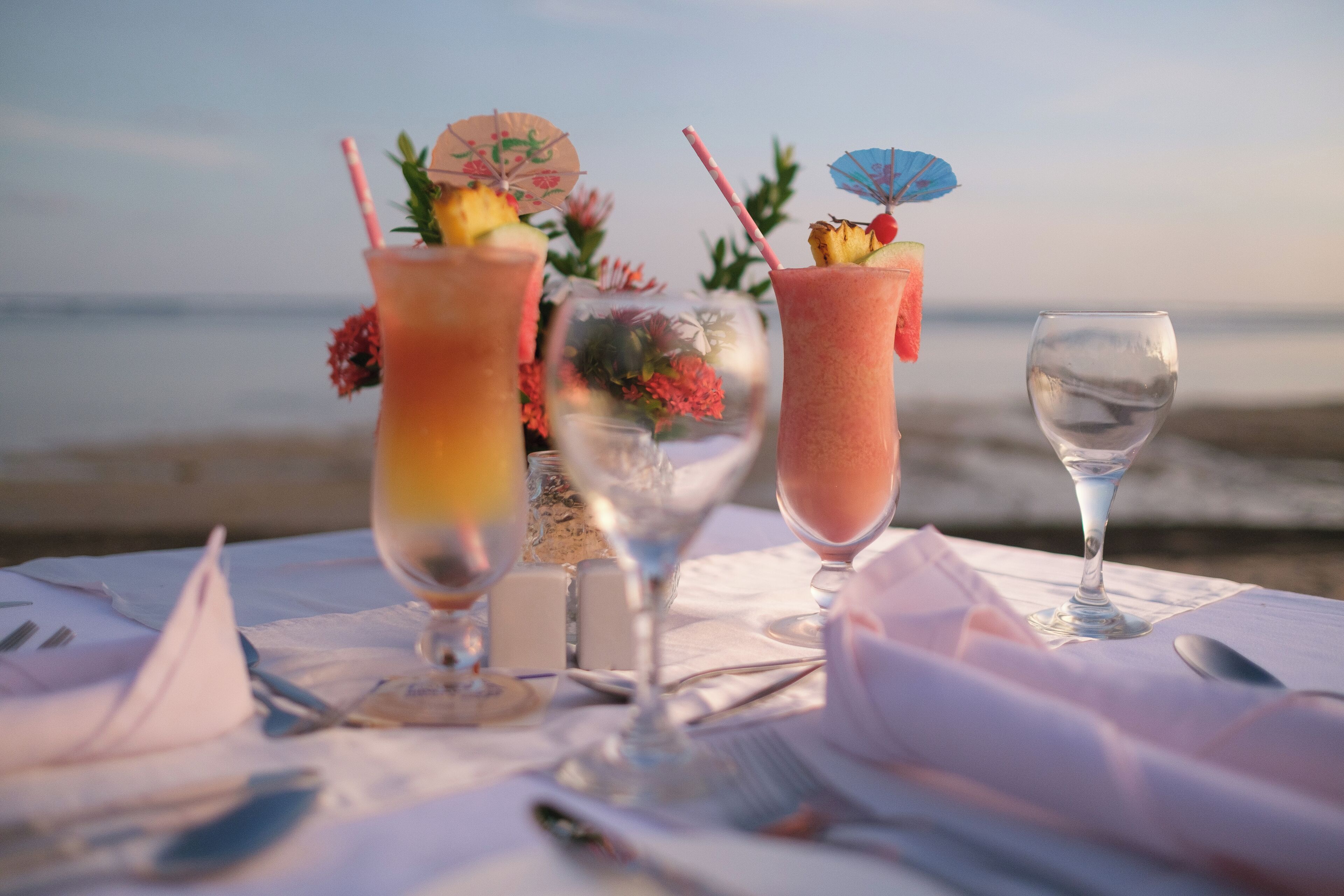 A table set with drinks and a glass of water on a beach.