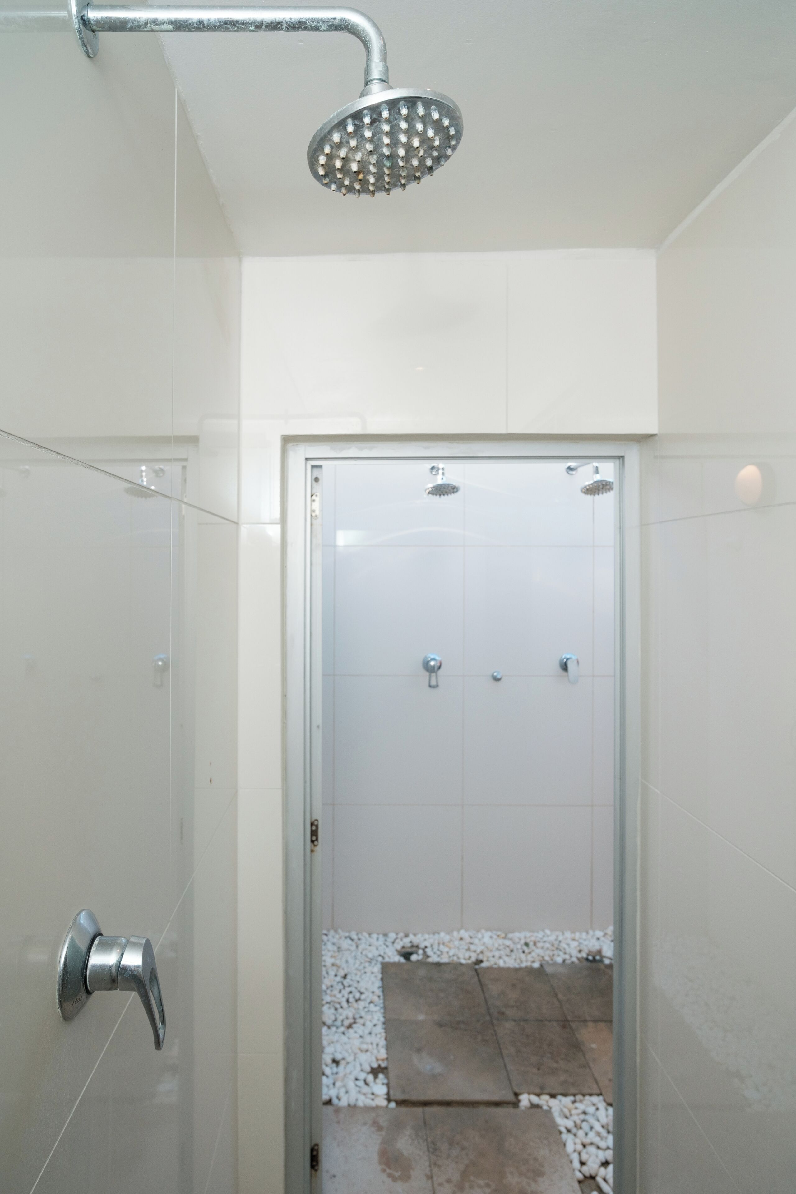 Un baño moderno con puerta de cristal, cabezal de ducha y suelo de baldosas a la vista.
