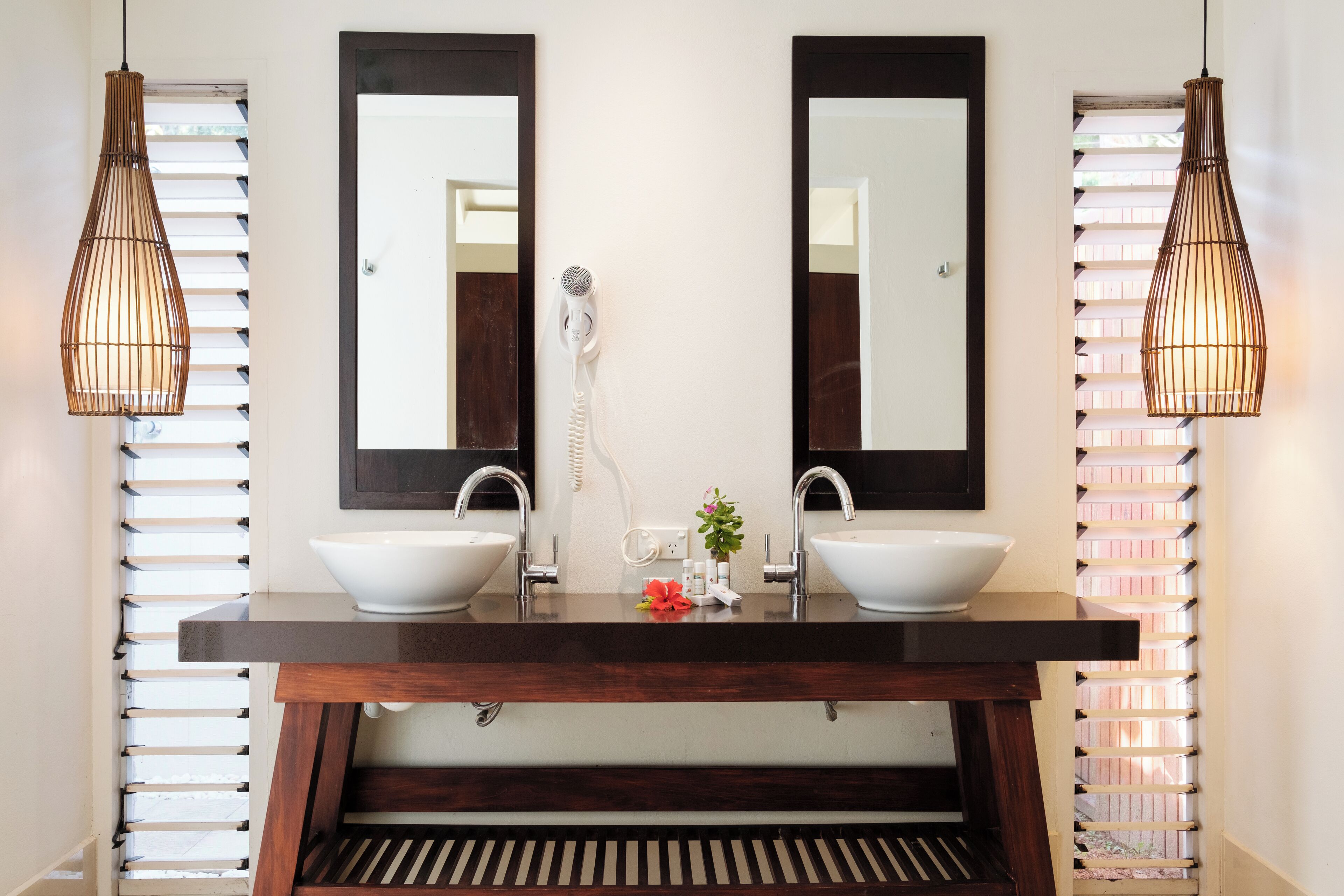 Une salle de bain avec un meuble-lavabo en bois, deux vasques et un grand miroir.