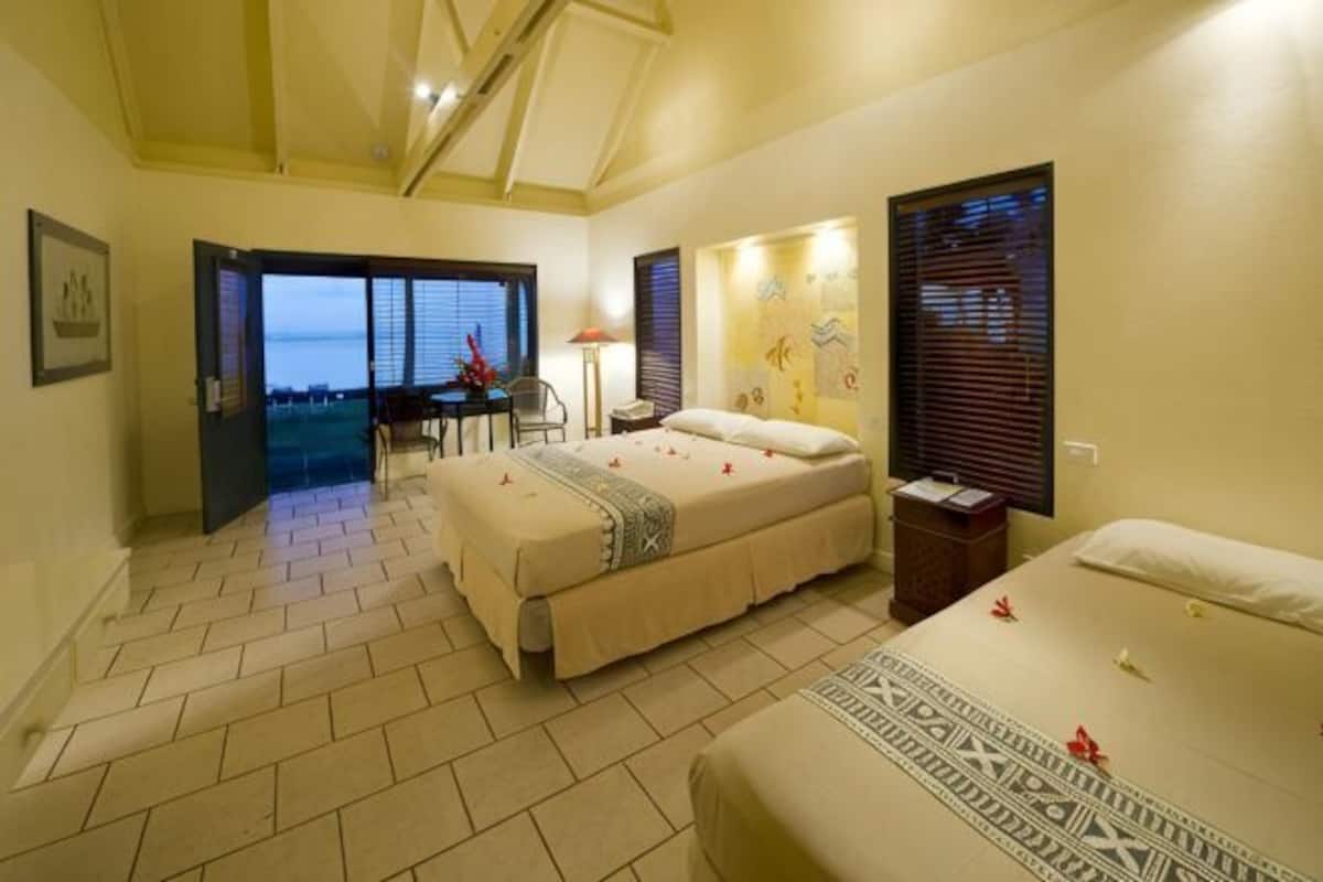 A bedroom with a bed, a desk, and a view through a door.