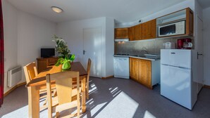 A compact kitchen with wooden cabinets, a microwave, a dishwasher, and a refrigerator. - Noemys les Toits du Devoluy (Le Dévoluy)