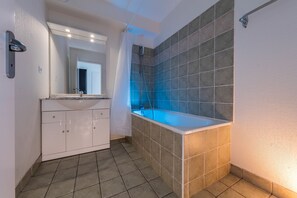 A bathroom with a bathtub, a sink, and a mirror.