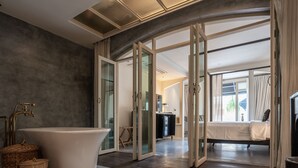 A modern bathroom with a freestanding bathtub, a large mirror, and a glass-enclosed shower area. - B House Samui (Koh Samui)