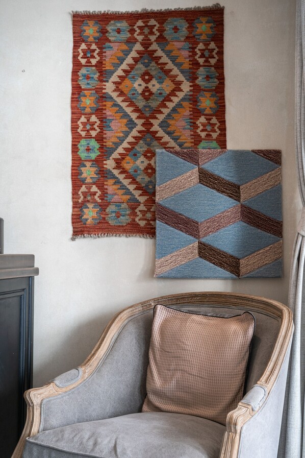A chair with a patterned cushion, a wall hanging with a geometric design, and a blue cushion with a similar pattern. - B House Samui (Koh Samui)