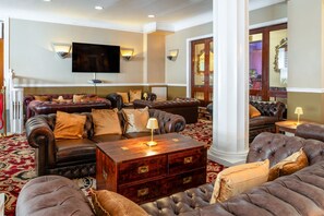 A spacious living room with leather sofas, a wooden coffee table, and a flat-screen TV mounted on the wall. - The Royal Hotel (Scarborough)