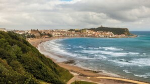 A coastal cityscape with a beach, a fortified hilltop, and a mix of residential and historical buildings. - The Royal Hotel (Scarborough)