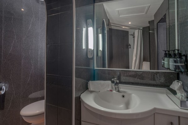A modern bathroom with a white sink, a mirror, and a toilet.