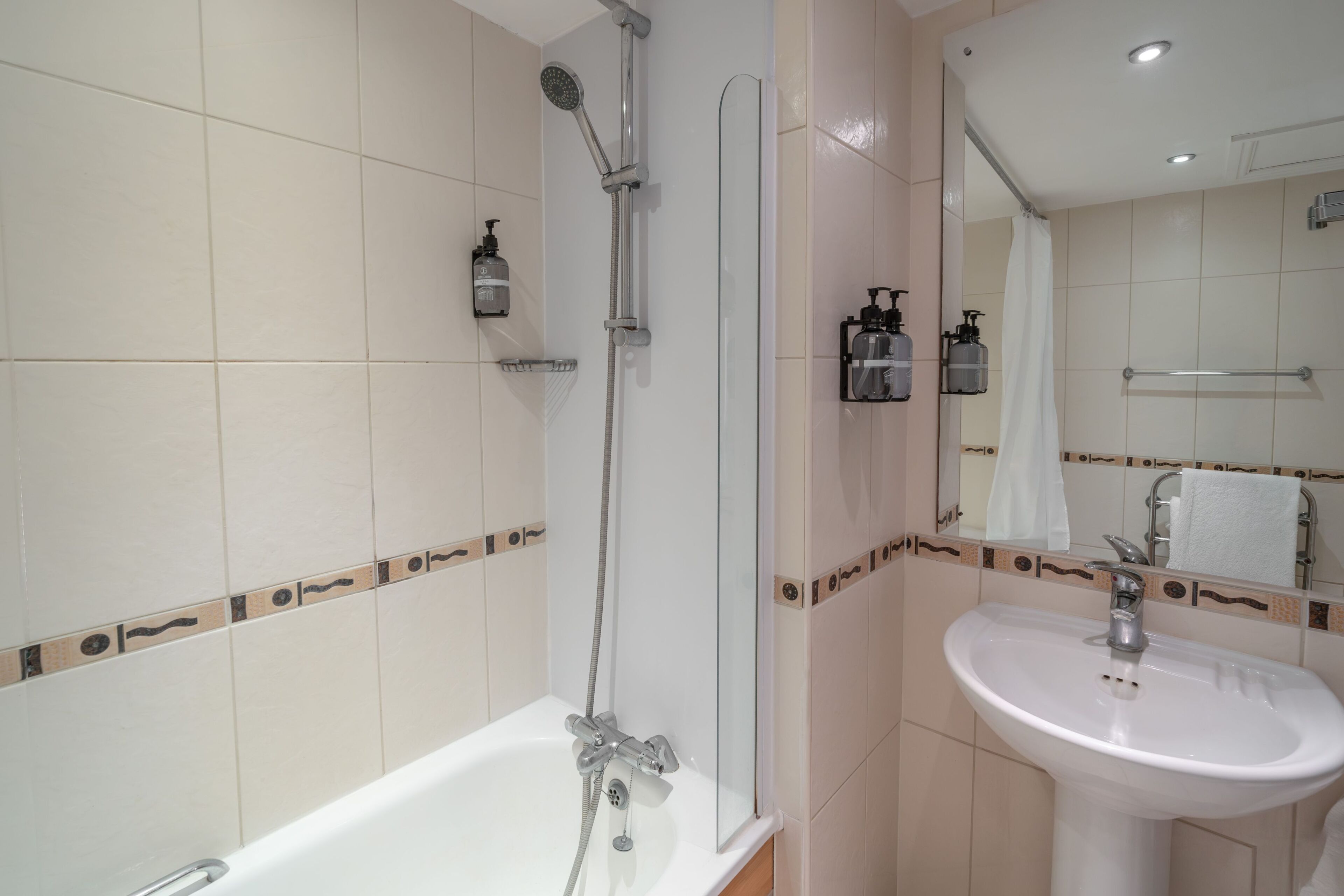 A bathroom with a bathtub, a shower, a sink, and a mirror.