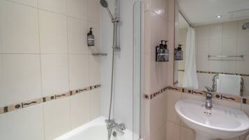 A bathroom with a bathtub, a shower, a sink, and a mirror.
