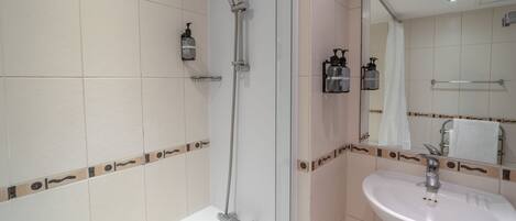 A bathroom with a bathtub, a shower, a sink, and a mirror.