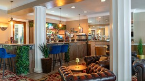 A bar area with stools, a counter, and a seating area with a round table and leather sofas. - The Royal Hotel (Scarborough)