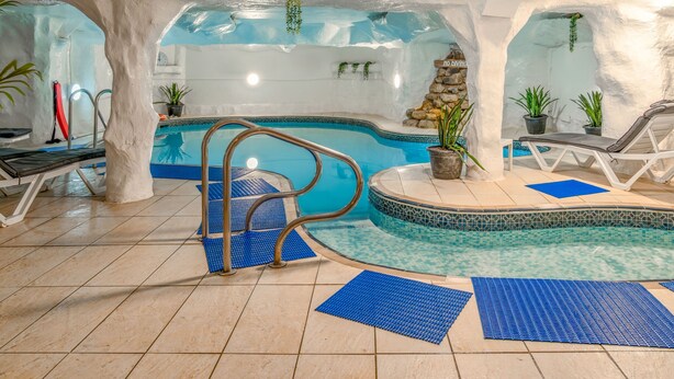 An indoor pool with a blue and white color scheme, surrounded by white walls and stone accents. - The Royal Hotel (Scarborough)