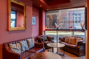 A room with a large mirror, two leather sofas, a round coffee table, and a window with blinds.
