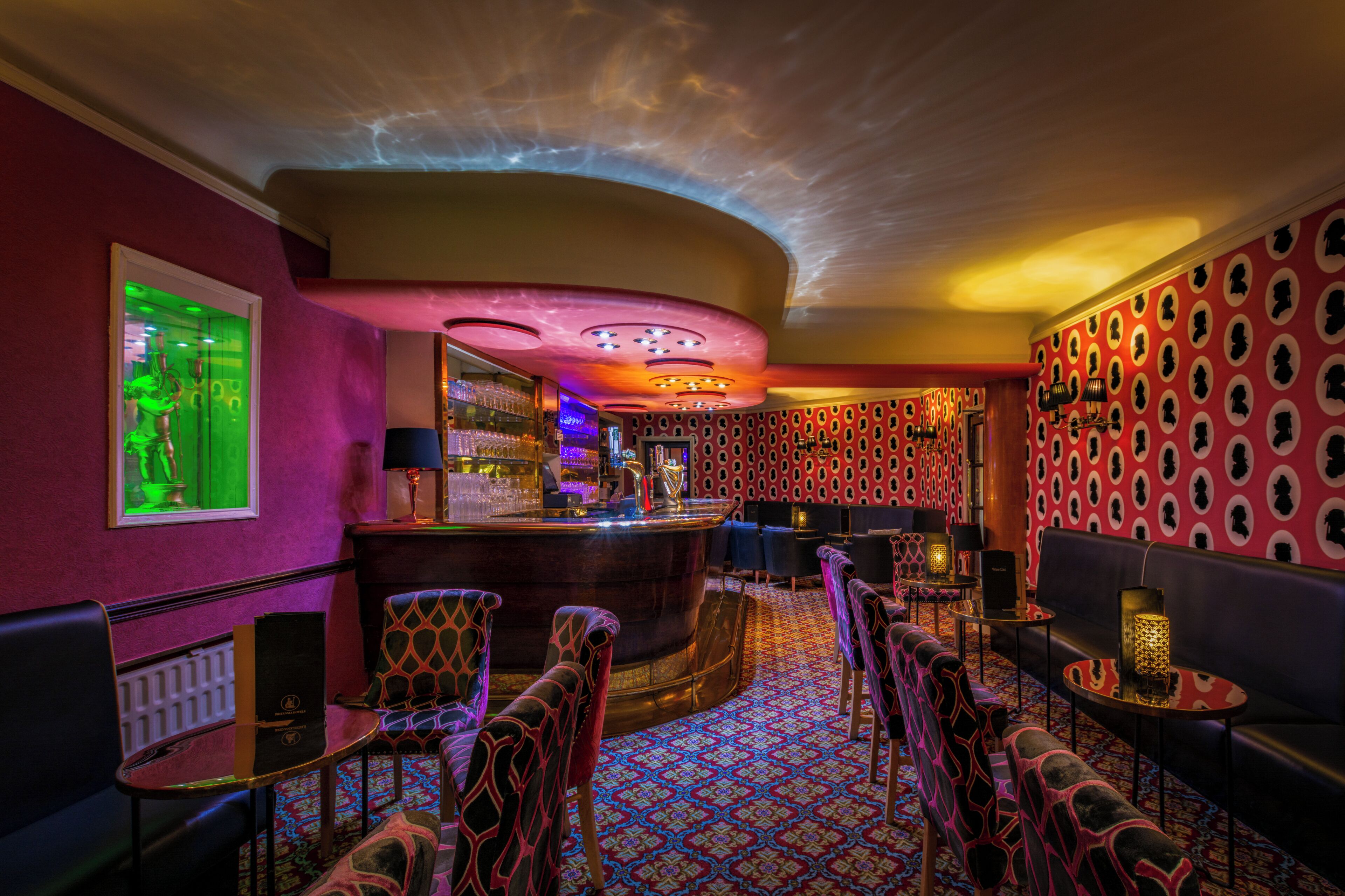 A bar area with a curved counter, bar stools, and a patterned carpet.
