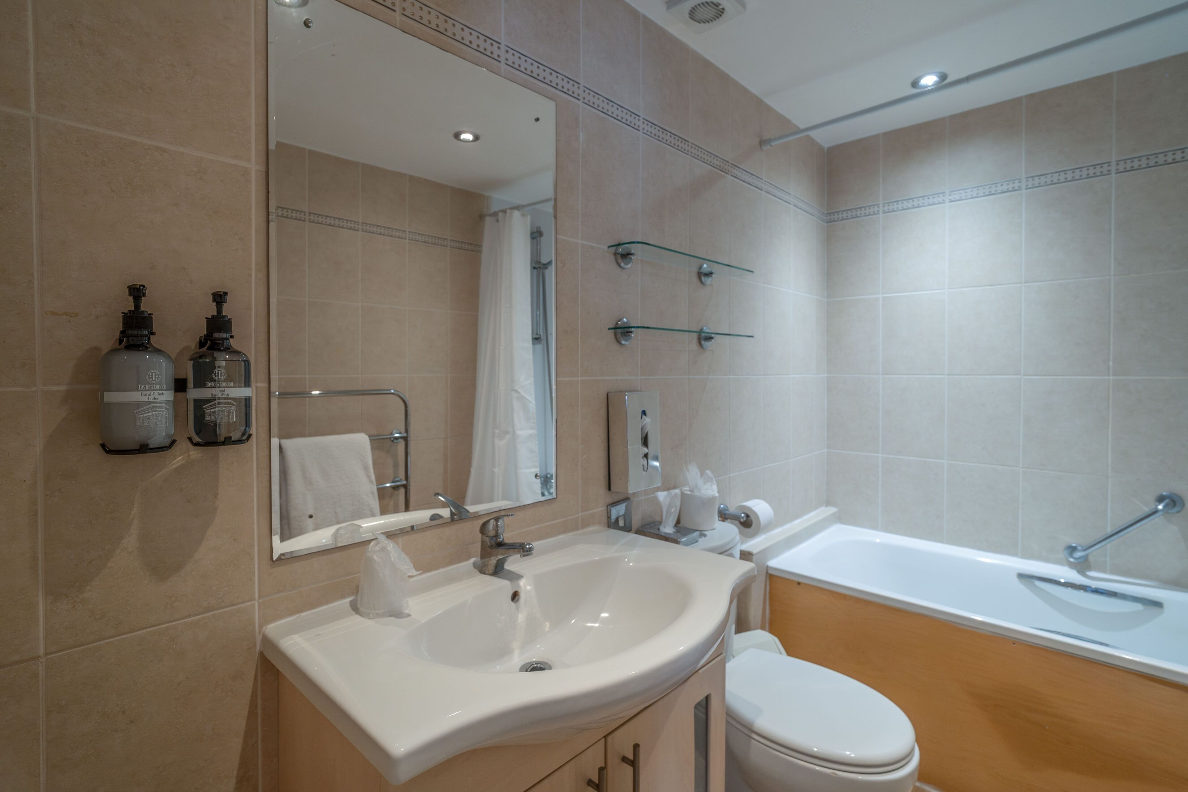A bathroom with a sink, mirror, toilet, and bathtub.