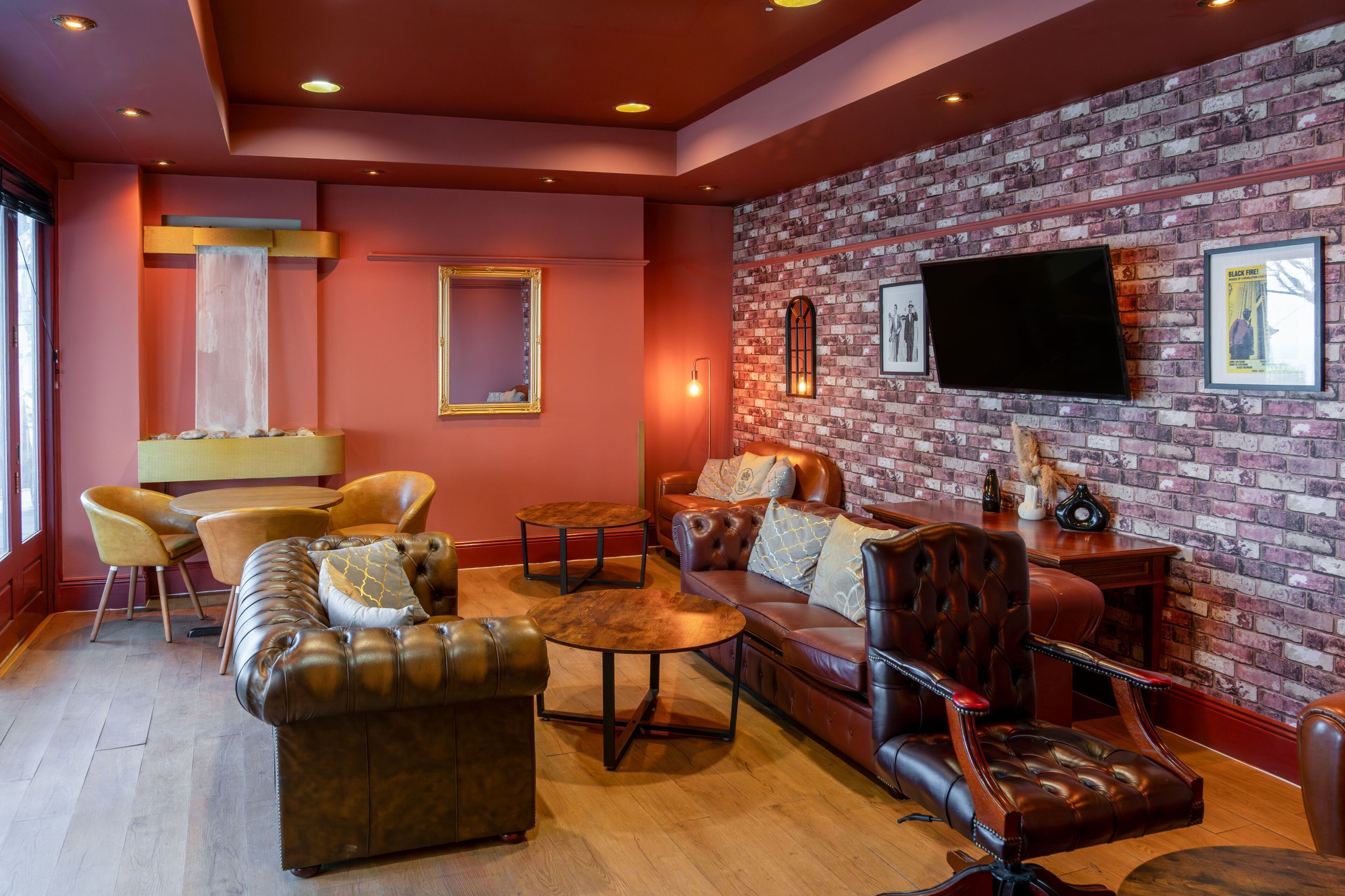 A cozy living room with leather sofas, a brick wall, a flat-screen TV, and a fireplace.