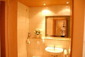 Un baño con lavamanos, espejo e inodoro.