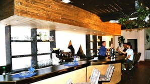 A bar area with a wooden ceiling, bar stools, and a counter with bottles and glasses. - Edelweiß (Goetzens)