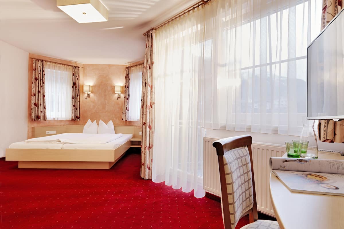 Une chambre d’hôtel avec un grand lit, un bureau avec une chaise et un téléviseur.
