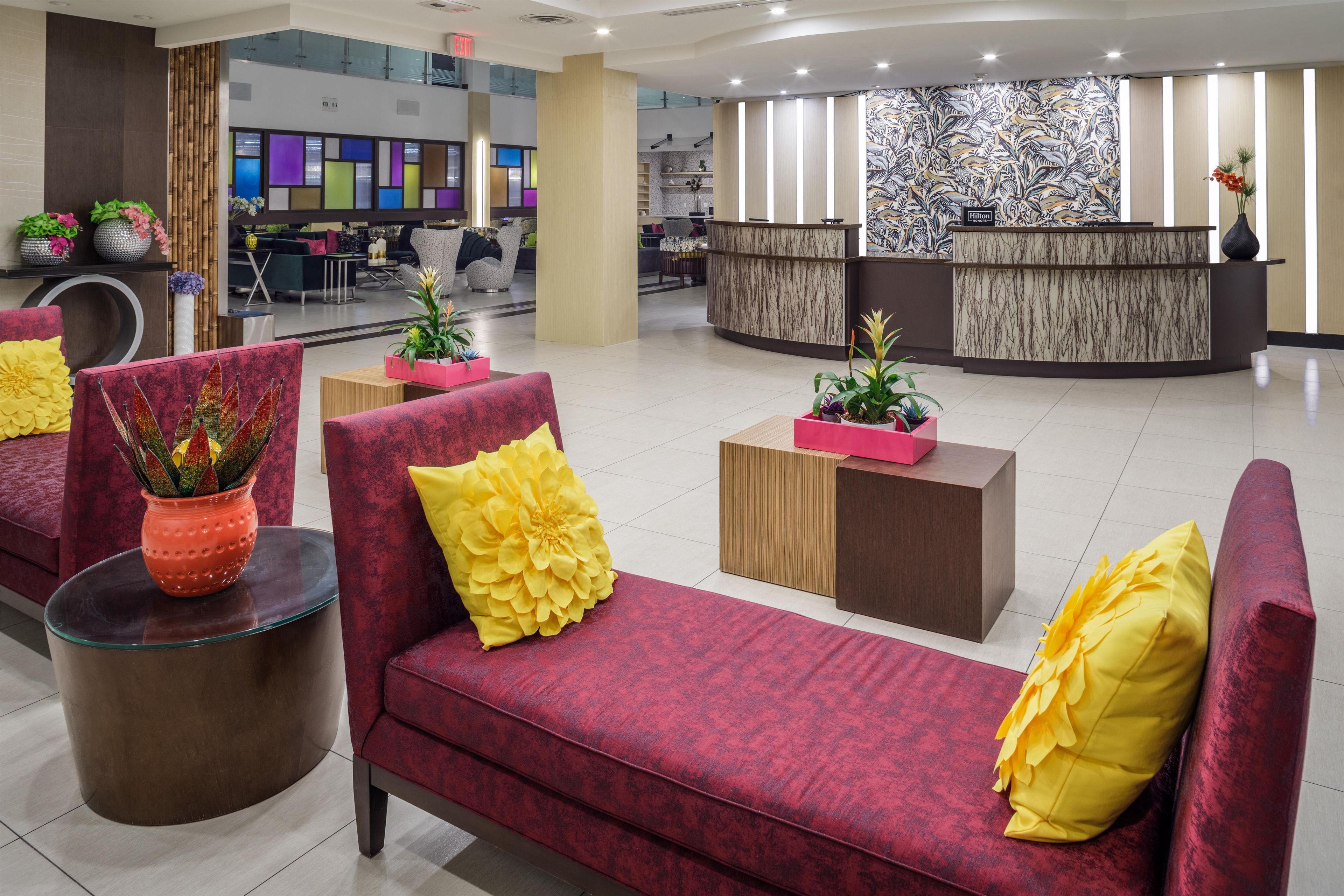 A hotel lobby with red sofas, a reception desk, and a modern interior design.